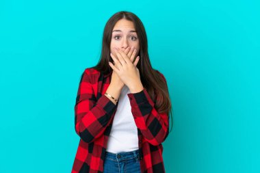 Genç Ukraynalı bir kadın mavi arka planda izole edilmiş, ağzı elleriyle kapatıyor.