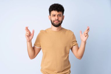 Faslı genç bir adam mavi arka planda izole edilmiş ve şans diliyor.