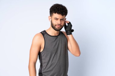 Genç Faslı bir adam mavi arka planda izole edilmiş müzik dinliyor.