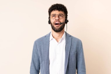 Faslı bir pazarlamacı bej arka planda izole edilmiş bir kulaklıkla çalışıyor.