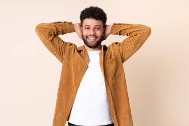 Faslı genç bir adam bej arka planda izole edilmiş gülüyor.