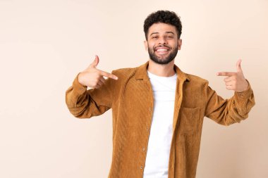 Faslı genç adam bej arka planda soyutlanmış gururlu ve kendini beğenmiş.