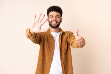 Faslı genç adam bej arka planda izole edilmiş. Parmakları olan altı kişi saydım.
