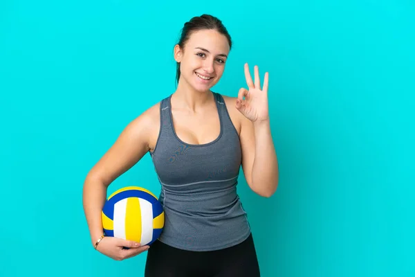 年轻的乌克兰女子打蓝色背景的排球 用手指表示可控标志 — 图库照片