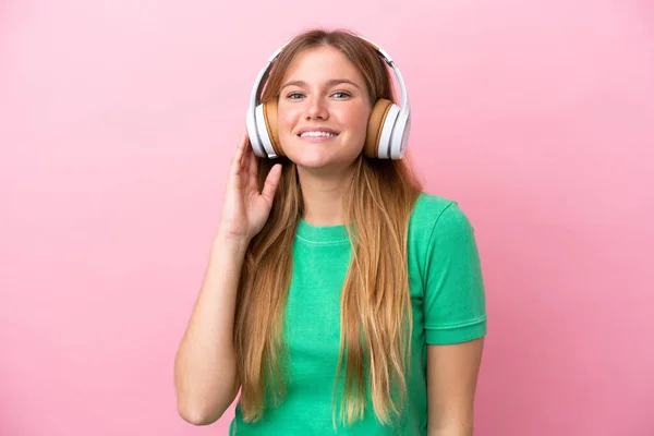 若いですブロンド女性絶縁上のピンクの背景リスニング音楽 — ストック写真