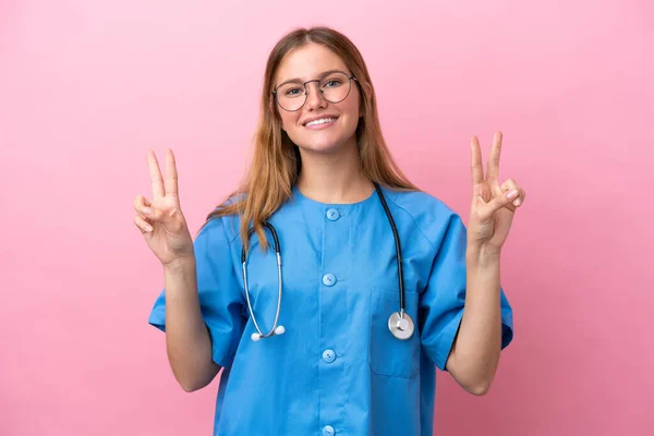 Junge Chirurg Ärztin Isoliert Auf Rosa Hintergrund Zeigt Siegeszeichen Mit — Stockfoto
