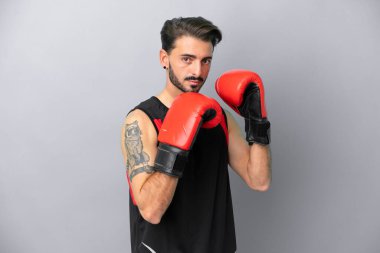 Gri arka planda boks eldivenli, beyaz, genç bir adam.