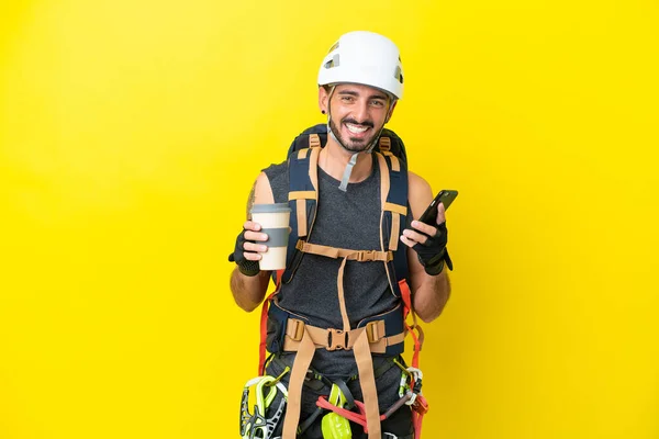 Jonge Kaukasische Bergbeklimmer Man Geïsoleerd Gele Achtergrond Met Koffie Mee — Stockfoto