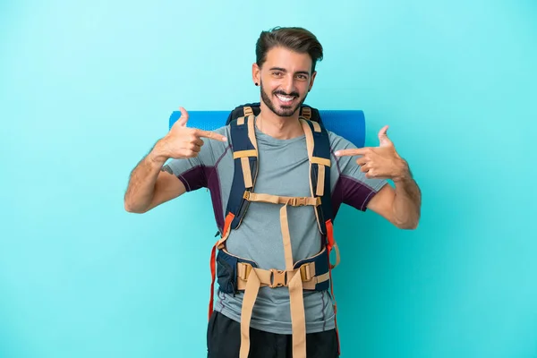 Junger Bergsteiger Mit Einem Großen Rucksack Isoliert Auf Blauem Hintergrund — Stockfoto