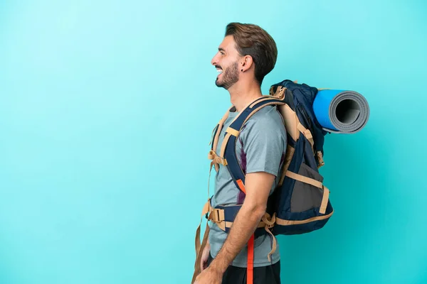 Joven Montañero Con Una Gran Mochila Aislada Sobre Fondo Azul —  Fotos de Stock