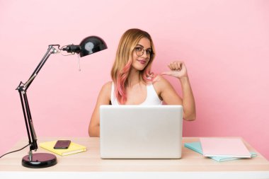 Pembe arka planda dizüstü bilgisayarı olan genç bir bayan öğrenci gururlu ve kendini beğenmiş.