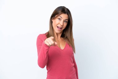 Beyaz arka planda izole edilmiş orta yaşlı beyaz kadın şaşırmış ve ön tarafı işaret ediyor.