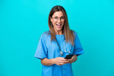 Mavi arka planda izole edilmiş orta yaşlı cerrah kadın şaşırdı ve bir mesaj gönderiyor.