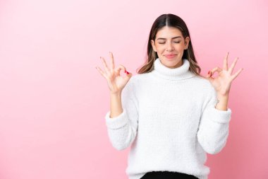 Zen pozisyonunda pembe arka planda izole edilmiş genç İtalyan kadın.