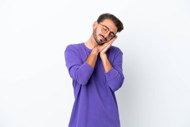 Beyaz arka planda izole edilmiş genç beyaz bir adam uyku jesti yapıyor.