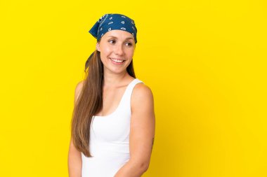 Sarı arka planda izole edilmiş genç bir İngiliz kadın yana bakıyor ve gülümsüyor.