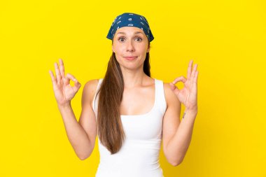 Zen pozunda sarı arka planda izole edilmiş genç İngiliz kadın.