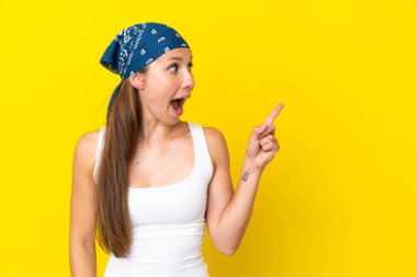 Sarı arka planda izole edilmiş genç İngiliz kadın parmağını kaldırarak çözümü anlamaya çalışıyor.