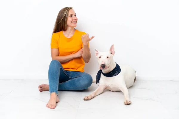 彼女の犬と一緒に床に座っている若い英語の女性は 製品を提示する側を指している白い背景に隔離されています — ストック写真