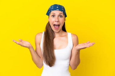 Sarı arka planda izole edilmiş genç İngiliz kadın şok olmuş yüz ifadesi ile
