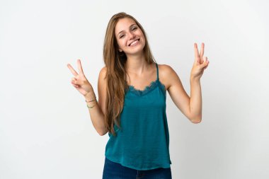 İzole edilmiş arka planda genç beyaz kadın iki eliyle zafer işareti gösteriyor.