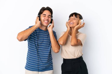 Beyaz arka planda izole edilmiş genç melez arkadaşlar müzik dinliyor ve şarkı söylüyorlar.