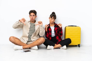 Genç, melez bir çift, beyaz arka planda izole bir şekilde yerde oturuyor. Kendini beğenmiş ve gururlu bir şekilde aşk konseptine sahip.