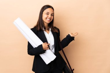 Genç mimar kadın izole edilmiş arka planda planları tutuyor. Davet edilmek için ellerini yana uzatıyor.