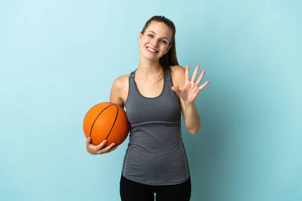 Młoda Kobieta Gra Koszykówkę Odizolowana Niebieskim Tle Licząc Pięć Palcami — Zdjęcie stockowe