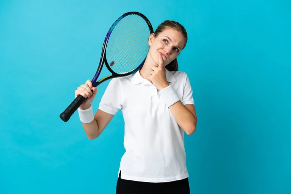 若いです女性テニスプレーヤー隔離上の青背景持っています疑問ながら上を見ます — ストック写真