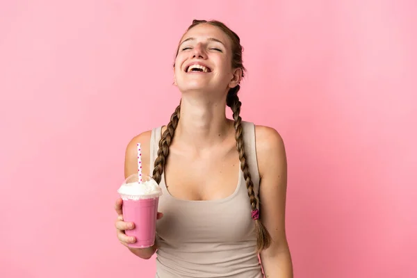 年轻女子与草莓奶昔隔离粉红背景笑 — 图库照片