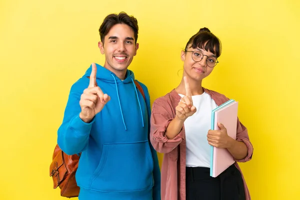 Junges Studentenpaar Isoliert Auf Gelbem Hintergrund Zeigt Und Hebt Einen — Stockfoto