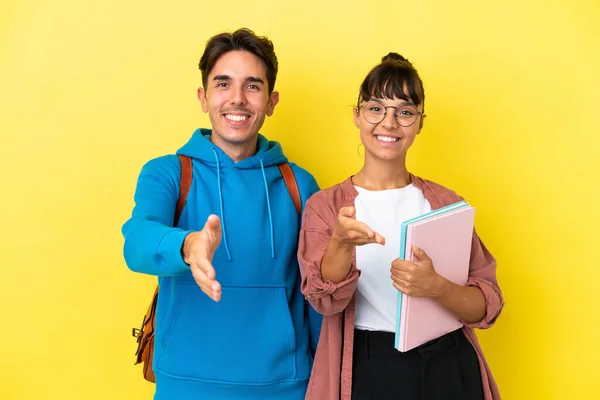 Junges Studentenpaar Isoliert Auf Gelbem Hintergrund Schüttelt Hände Ein Gutes — Stockfoto