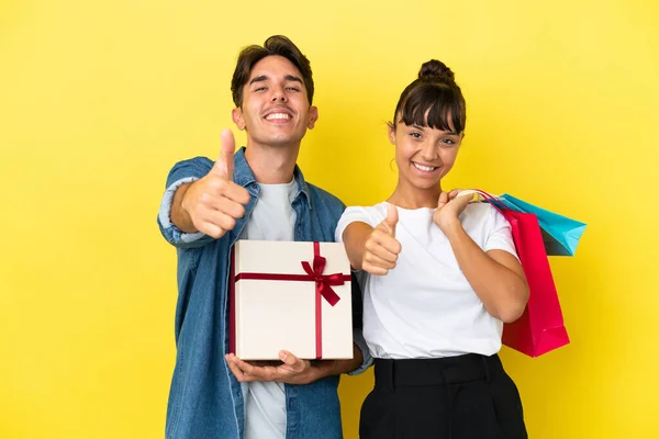 Casal Jovem Segurando Sacos Compras Presente Isolado Fundo Amarelo Dando — Fotografia de Stock