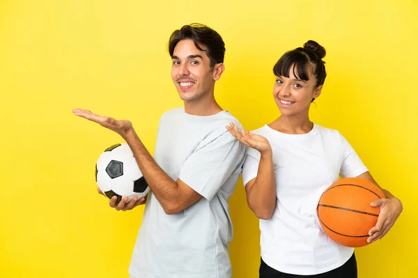 Young Sport Couple Playing Football Basketball Isolated Yellow Background Pointing — Stock Photo, Image