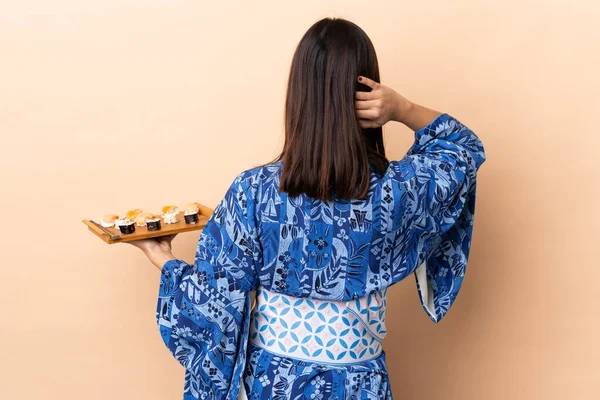 Frau Trägt Kimono Und Hält Sushi Über Isoliertem Hintergrund Rückenlage — Stockfoto