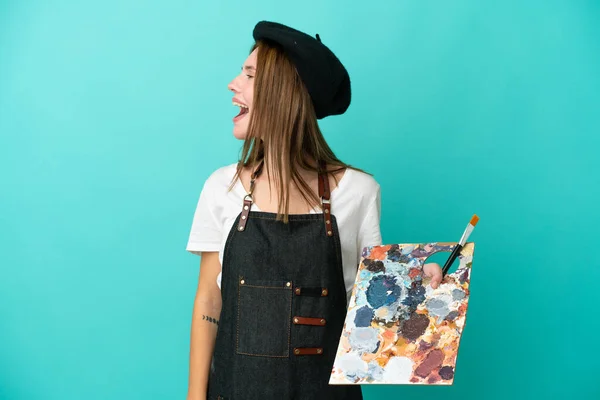 Νεαρή Αγγλίδα Καλλιτέχνιδα Κρατώντας Μια Παλέτα Απομονωμένη Μπλε Φόντο Γελώντας — Φωτογραφία Αρχείου