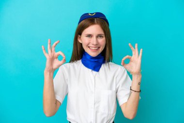 Uçak hostesi İngiliz kadın mavi arka planda izole edilmiş, parmaklarıyla 