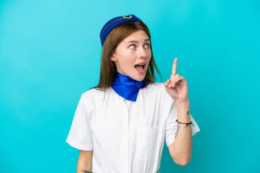 Uçak hostesi İngiliz kadın mavi arka planda izole edilmişti. Çözümü, parmağını kaldırarak bulmaya çalışıyordu.