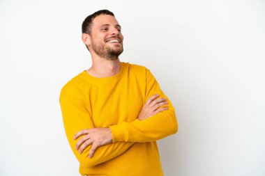 Genç Brezilyalı adam beyaz arka planda yalnız mutlu ve gülümsüyor.