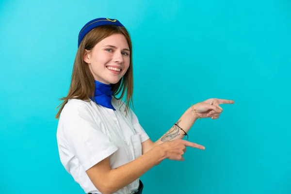 飛行機スチュワーデス側に指を指して 製品を提示青い背景に隔離された英語の女性 — ストック写真