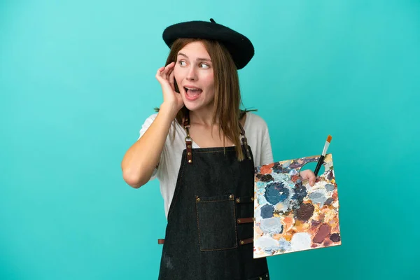 Νεαρή Αγγλίδα Καλλιτέχνιδα Κρατώντας Μια Παλέτα Απομονωμένη Μπλε Φόντο Ακούγοντας — Φωτογραφία Αρχείου