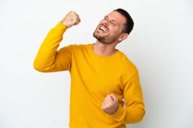 Genç Brezilyalı izole edilmiş beyaz arka planda zaferi kutluyor.