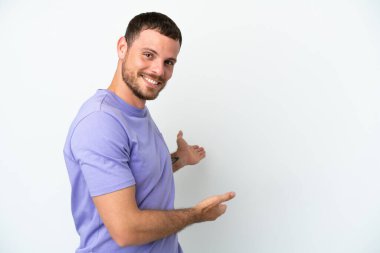 Beyaz arka planda izole edilmiş genç Brezilyalı adam, davet etmek için ellerini yana uzatıyor.