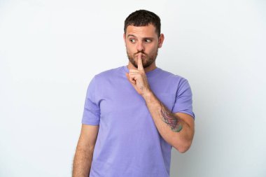 Beyaz arka planda izole edilmiş genç Brezilyalı bir adam sessizlik işareti gösteriyor. Parmağını ağzına sokuyor.