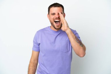 Beyaz arka planda izole edilmiş genç Brezilyalı adam ağzı açık bağırıyor.