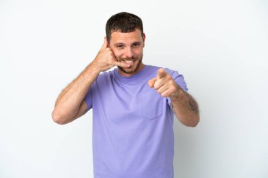 Beyaz arka planda izole edilmiş genç Brezilyalı bir adam telefon hareketi yapıyor ve ön tarafı işaret ediyor.