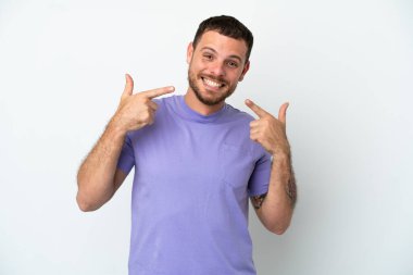 Beyaz arka planda izole edilmiş genç Brezilyalı bir adam baş parmak hareketi yapıyor.