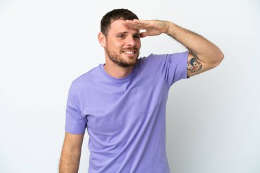 Genç Brezilyalı bir adam beyaz arka planda izole edilmiş. Bir şeye bakmak için uzaklara bakıyor.