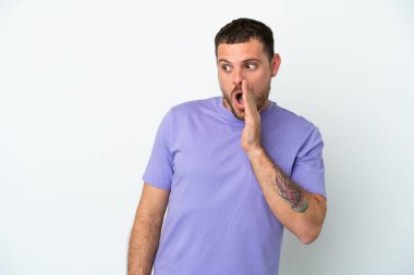 Genç Brezilyalı bir adam beyaz arka planda izole edilmiş. Yan tarafa bakarken sürpriz bir jest yapıyor.